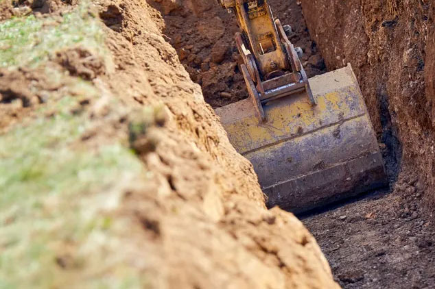 Photo of an excavator digging a trench for underground utilities